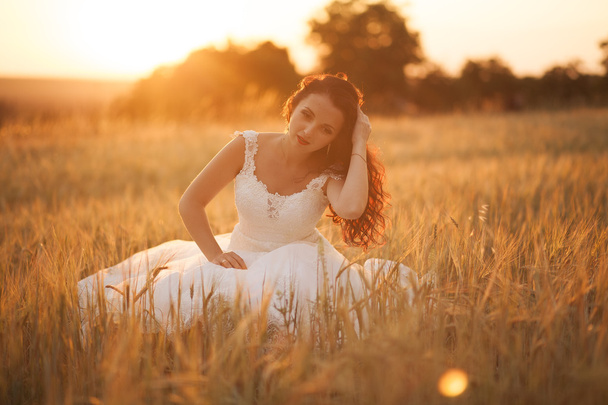 Happy beautiful young bride outside on a summer meadow at the sunset - Photo, Image