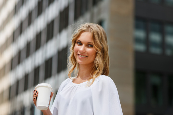 Portrait of smiling blond woman on business center background - Foto, Imagem