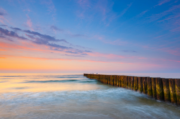 puesta de sol en la playa con un rompeolas de madera, larga exposición
 - Foto, imagen
