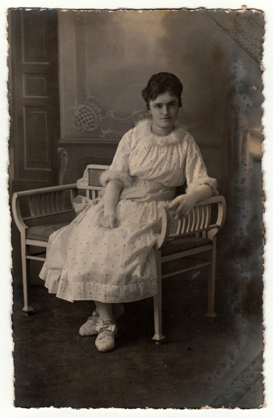 Vintage φωτογραφία δείχνει γυναίκα κάθεται σε ένα πάγκο λευκό τελεία. Ρετρό μαύρη & λευκή φωτογραφία στούντιο. - Φωτογραφία, εικόνα