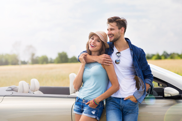 Young couple standing near convertible - 写真・画像