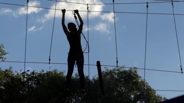 Girl on High Altitude Goes Through the Ropes. Entretenimiento en el parque de cuerdas
. - Metraje, vídeo