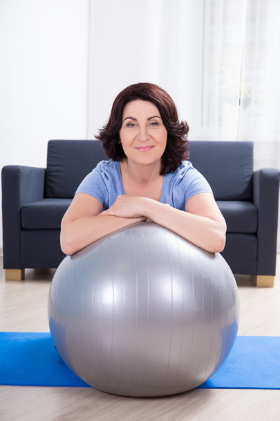 slim sporty mature woman doing exercises with fitness ball at ho - Fotografie, Obrázek