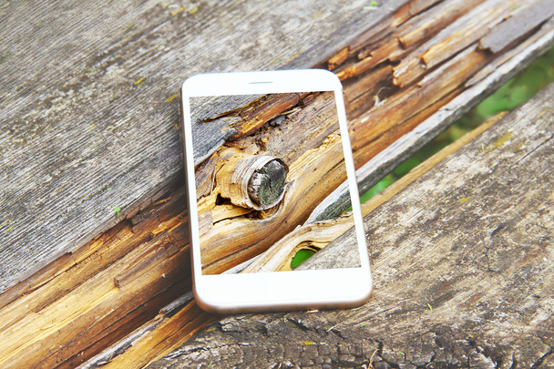 Smartphone με διάφανη οθόνη συγκρατείται σε ξύλινο πάγκο. - Φωτογραφία, εικόνα