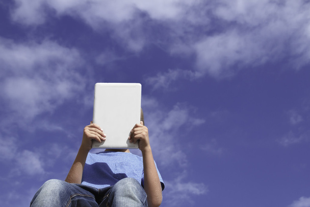 Niño con tablet PC contra el cielo azul. Vista de ángulo bajo. Infancia, tecnología, educación, concepto de ocio
 - Foto, Imagen