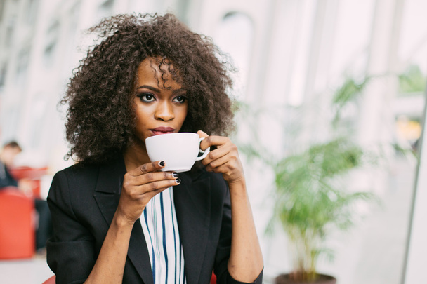 Close up portrait of a happy young african american woman with cup coffee - Foto, Imagen