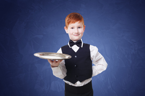 Mały chłopiec kelner stoi pusta taca serwujemy coś - Zdjęcie, obraz
