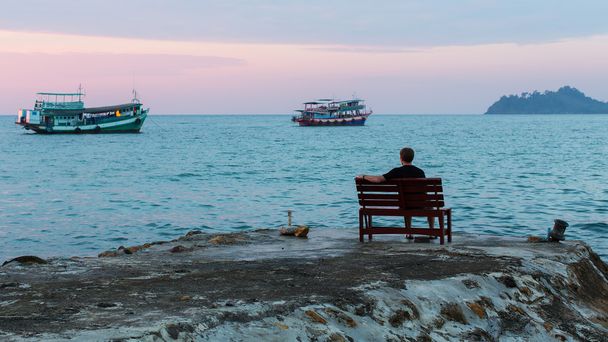 man zittend op zee Pier - Foto, afbeelding