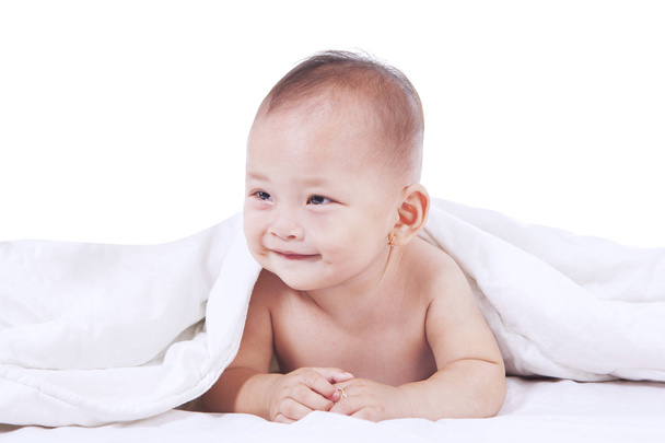 Cute baby lying under blanket and smiling - Foto, immagini