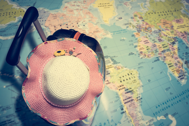 Sac de voyage avec chapeau de paille sur la carte du monde
 - Photo, image