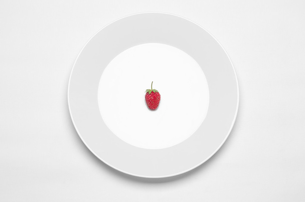 Healthy eating in the restaurant and diet Topic: white plate with a strawberry lying on a white table in the studio isolated top view - Fotó, kép