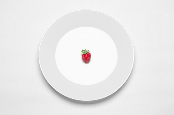 Healthy eating in the restaurant and diet Topic: white plate with a strawberry lying on a white table in the studio isolated top view - Fotoğraf, Görsel