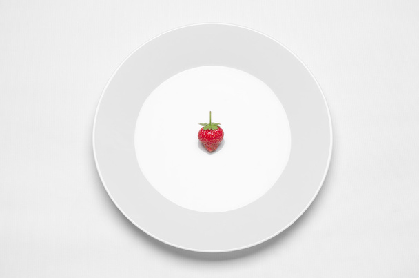 Egészséges táplálkozás az étteremben és a diéta téma: fehér lemez, eper feküdt egy fehér asztal a stúdióban izolált felülnézet - Fotó, kép