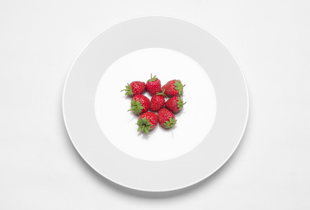 Healthy eating in the restaurant and diet Topic: white plate with strawberries lying on a white table in the studio isolated top view - Fotó, kép