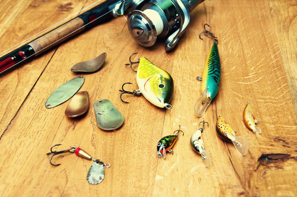 Fishing baits and rod isolated on wooden background - Фото, изображение