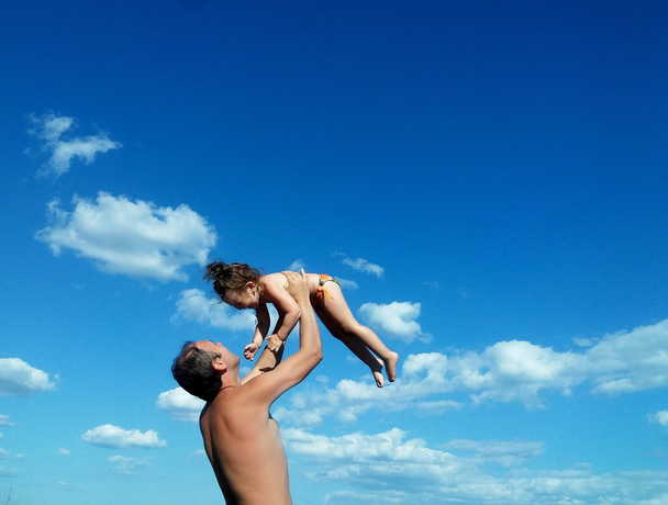 Vader gooit gelukkige dochter tegen de hemel - Foto, afbeelding