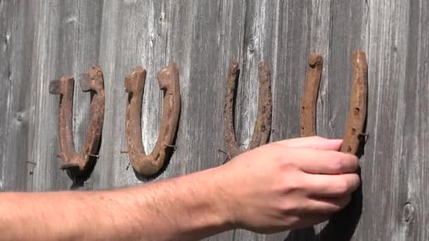 Ország ember kéz unhang régi rozsdás patkókat, a régi, fából készült ajtó - a szerencse szimbóluma. 4k - Felvétel, videó