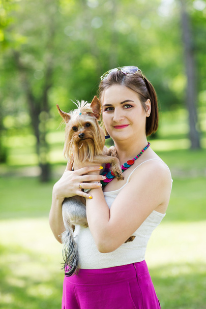 Beautiful young happy woman holding small dog in summer day walks in park - Foto, Imagem