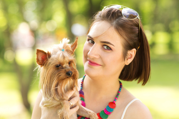 Beautiful young happy woman holding small dog in summer day walks in park - Foto, imagen