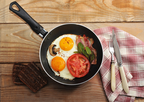 bacon and eggs and mushrooms with the pan on wooden background i - Фото, зображення