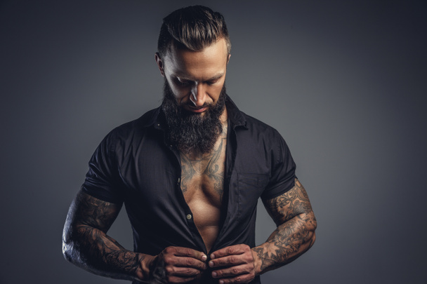 Tattooed male taking off his shirt - Photo, Image