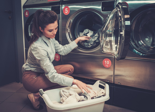Beautiful woman doing laundry at laundromat shop. - Foto, Bild