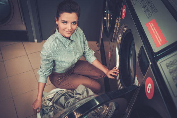 Beautiful woman doing laundry at laundromat shop. - Valokuva, kuva