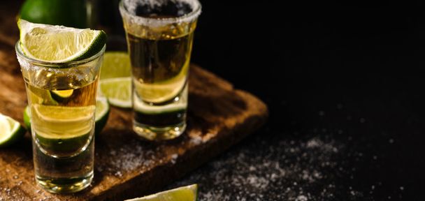 Tequila de oro mexicano con lima y sal sobre mesa de madera
 - Foto, imagen
