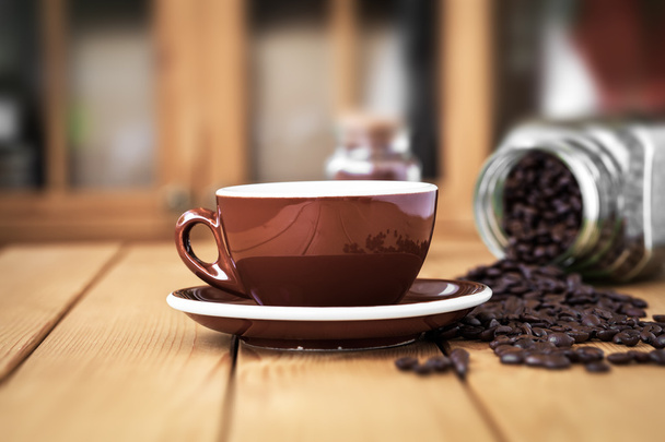 Dağınık kahve çekirdekleri ile ahşap bir masa üzerinde kahve Kupası - Fotoğraf, Görsel