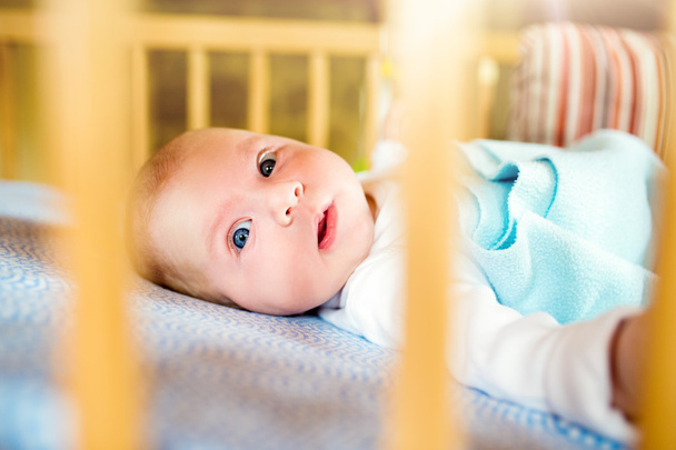 Little baby boy lying in wooden crib, close up - Fotó, kép