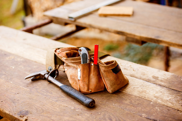 Carpenters bag with belt full of tools, wooden table - Zdjęcie, obraz