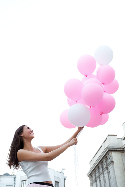 Portrait of beautiful brunette with pink air balloons against of sky - Valokuva, kuva