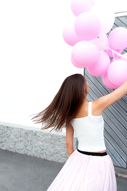 back view of brunette with flying hair dancing with pink balloons - Zdjęcie, obraz