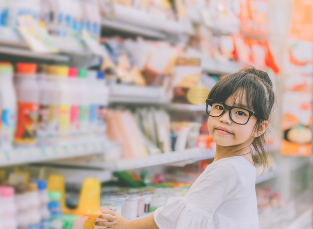 Meisje op het winkelcentrum, portret van een jong meisje op de status van de winkel in de buurt van de planken met snoep - Foto, afbeelding
