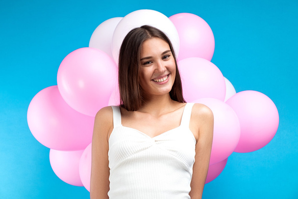 Portrait of attractive young girl with pink air balloons behind on blue background.Isolate - Fotó, kép