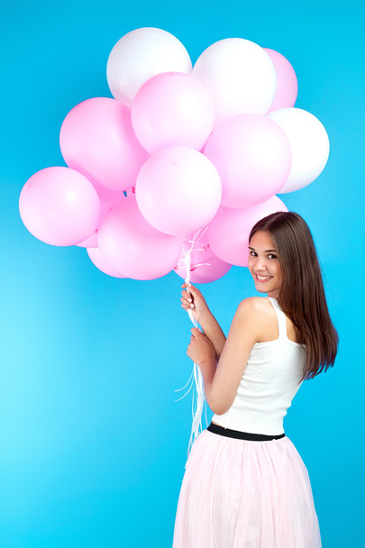 Rear view of beautiful brunette girl with many balloons smiling back at camera.Isolate - Foto, Bild