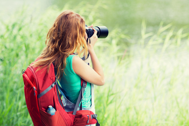 young woman with backpack and camera outdoors - Фото, изображение