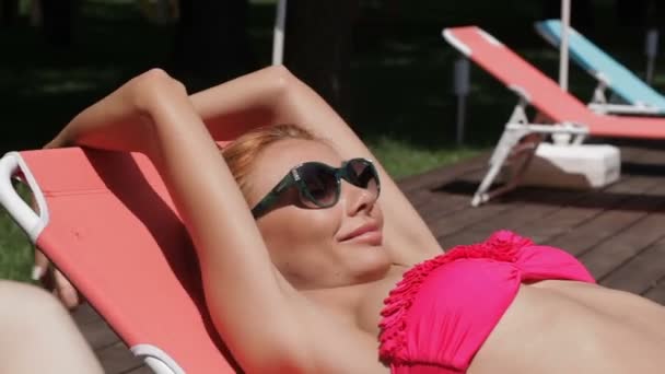 Frau genießt sonniges Wetter in Schwimmbadnähe - Filmmaterial, Video