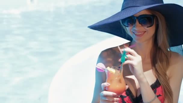 Woman poses with glass of coktail near the swimming pool - Filmagem, Vídeo