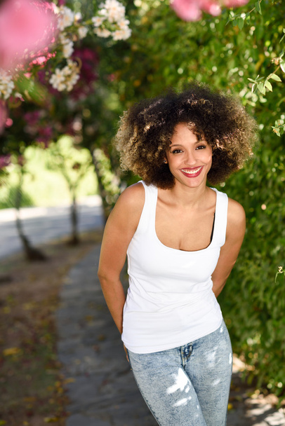 Joven mujer negra con peinado afro sonriendo en parque urbano
 - Foto, imagen