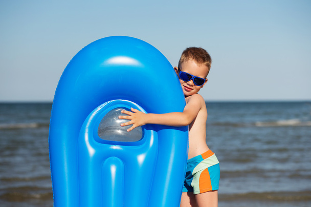 Garçon souriant jouant sur la plage avec matelas gonflable
 - Photo, image