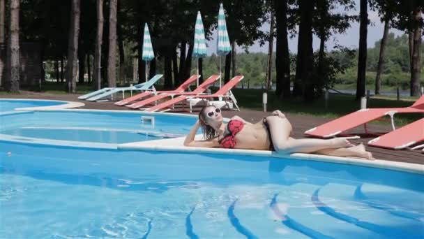 Long shot of woman lying on the pool edge - Πλάνα, βίντεο