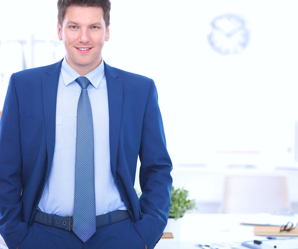 Деловой человек или менеджер, стоящий напротив своего стола в офисе - Фото, изображение