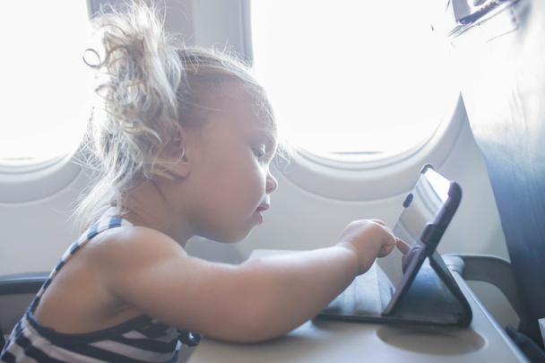 kid playing with tablet in plane. - Fotó, kép