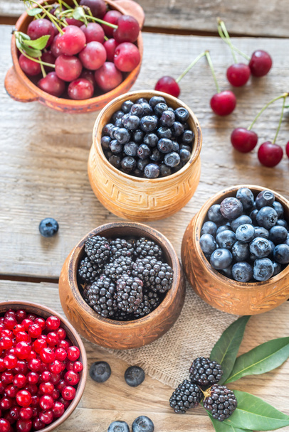 Bowls of summer berries on the wooden table - Photo, image