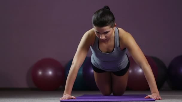 Young woman doing knee push-ups, working thoroughly to achieve fit body goal - Záběry, video