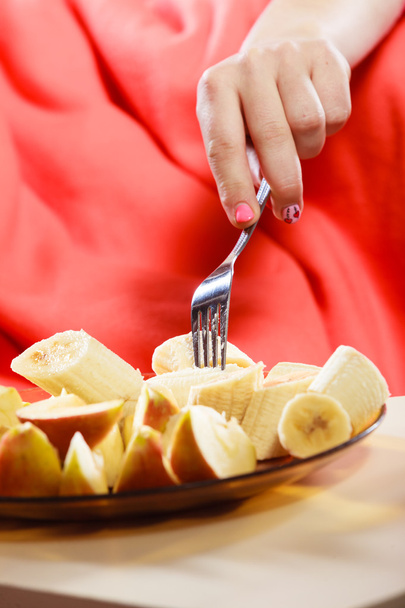 Woman hands taking forking banana and apple. - Photo, image