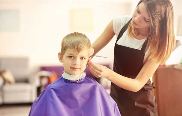 Hairdresser making hairstyle to child on blurred background - Fotó, kép