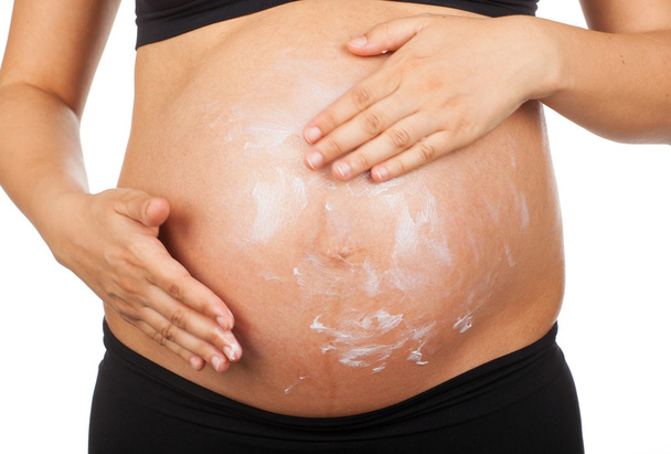 mujer embarazada masajeando su vientre con ungüento contra estiramiento
 - Foto, Imagen