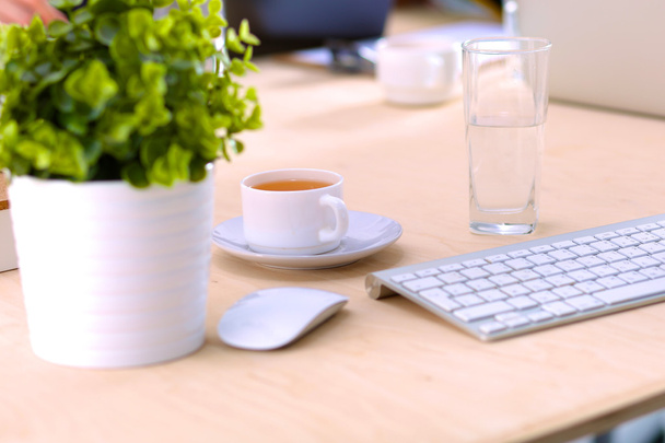 Close-up van een werk bureau interieur met een laptopcomputer, een kopje koffie en witte gordijnen op een zonnige dag - Foto, afbeelding